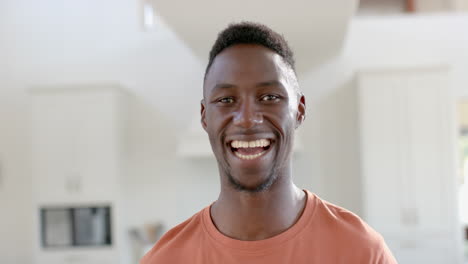 Happy-african-american-man-standing-and-laughing-in-sunny-living-room,-slow-motion