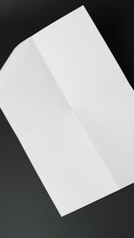 Vertical-video-of-piece-of-white-paper-with-creases-on-black-background