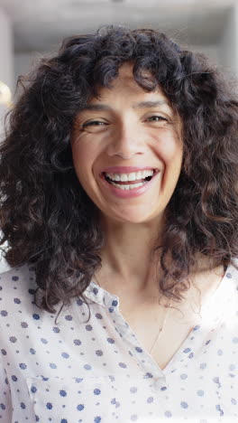 Vertical-video-of-portrait-of-happy-biracial-woman-with-curly-hair-at-home,-slow-motion