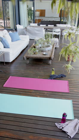 Water-bottles,-towels-and-exercising-mats-on-sunny-terrace