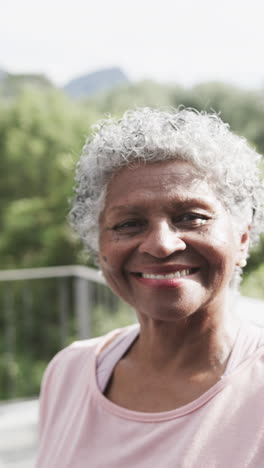 Retrato-En-Video-Vertical-De-Una-Feliz-Mujer-Afroamericana-Mayor-Sonriendo-En-El-Jardín,-Cámara-Lenta