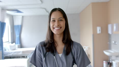 Retrato-De-Una-Doctora-Birracial-Sonriente-Con-El-Pelo-Largo-Y-Oscuro-En-La-Sala-Del-Hospital,-Cámara-Lenta