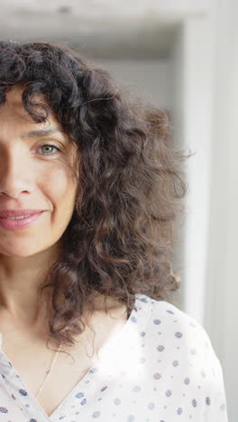 Vertical-video-half-portrait-of-mature-caucasian-woman-with-curly-hair-smiling,-slow-motion