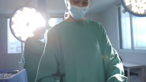 Portrait-of-biracial-female-surgeon-sorting-surgical-tools-in-theatre,-copy-space,-slow-motion