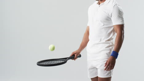 Un-Joven-Birracial-Vestido-De-Tenis-Juega-Con-Una-Pelota,-Con-Espacio-Para-Copiar