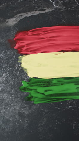 Vertical-video-of-red,-yellow-and-green-paints-with-copy-space-on-black-background
