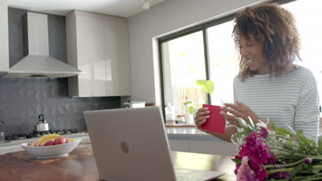 Mujer-Birracial-Feliz-Teniendo-Videollamada-Del-Día-De-San-Valentín-En-Una-Computadora-Portátil-En-Casa-Lanzando-Un-Beso,-Cámara-Lenta