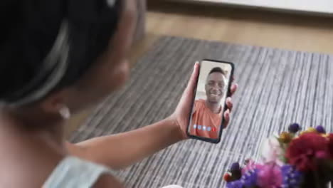 Mujer-Birracial-Sosteniendo-Un-Teléfono-Inteligente-Con-Un-Hombre-Afroamericano-En-La-Pantalla