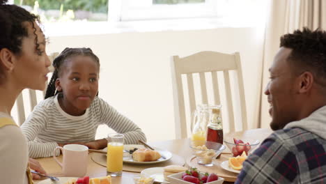 Happy-african-american-parents-and-daughter-having-breakfast-at-home,-slow-motion