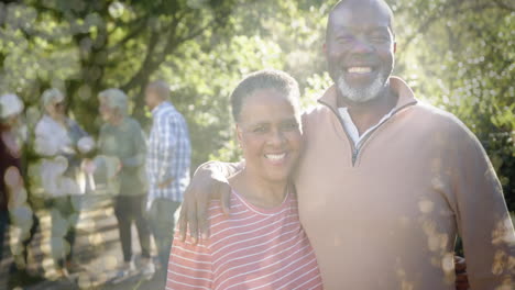 Animation-of-spots-of-light-over-diverse-senior-people-smiling-in-garden