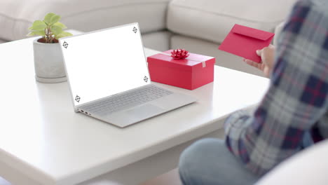 Caucasian-man-holding-envelope-and-using-laptop-with-copy-space-on-blank-screen