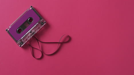 Video-of-retro-tape-with-pink-label-and-pulled-out-tape-with-copy-space-on-pink-background