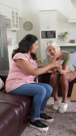 Happy-diverse-senior-women-using-smartphone-and-smiling-in-sunny-living-room,-slow-motion