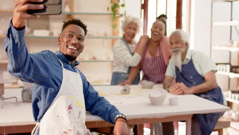 Happy-diverse-group-of-potters-doing-selfie-and-smiling-in-pottery-studio