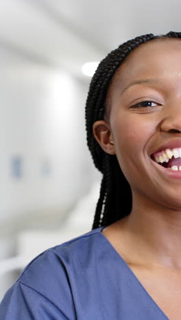 Vertical-video-of-portrait-of-happy-african-american-female-doctor-in-hospital,-slow-motion