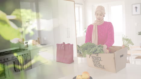 Mujer-Birracial-En-Hijab-Con-Caja-Con-Verduras-En-La-Cocina,-Sobre-Hojas