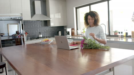 Happy-biracial-woman-having-valentine's-video-call-on-laptop-at-home,-copy-space,-slow-motion