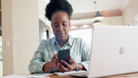 Feliz-Mujer-Mayor-Afroamericana-Usando-Laptop-Y-Teléfono-Inteligente-En-Una-Habitación-Soleada-En-Casa,-Cámara-Lenta