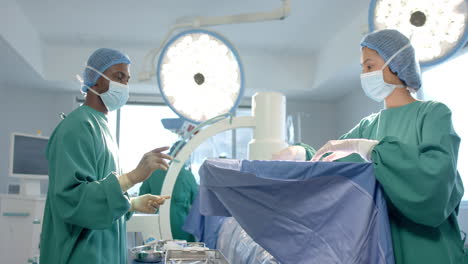 Diverse-female-and-male-surgeons-in-masks-talking-in-operating-theatre,-slow-motion