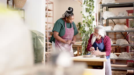 Focused-diverse-male-and-female-potters-using-potter's-wheel-in-pottery-studio,-slow-motion