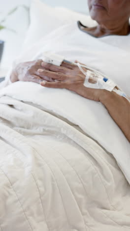 Vertical-video-of-senior-african-american-woman-hand-with-intravenous,-slow-motion,-copy-space