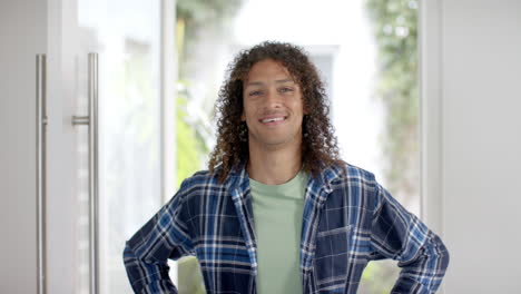 Retrato-De-Un-Hombre-Birracial-Feliz-Con-El-Pelo-Largo-Y-Rizado-Oscuro-En-La-Puerta-De-Casa,-Cámara-Lenta