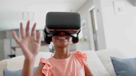 Happy-biracial-girl-wearing-vr-headset-using-virtual-interface-at-home,-slow-motion