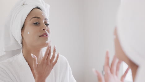 Mujer-Birracial-Aplicando-Crema-Facial-Mirando-En-El-Espejo-Del-Baño,-Cámara-Lenta