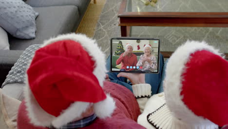 Dos-Felices-Parejas-Caucásicas-Mayores-Teniendo-Videollamadas-Con-Tabletas-Navideñas,-Cámara-Lenta