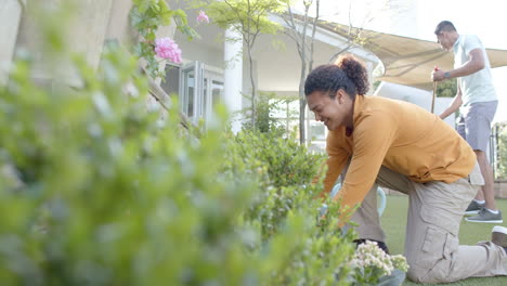 Happy-diverse-gay-male-couple-gardening-together-in-sunny-garden,-slow-motion,-copy-space