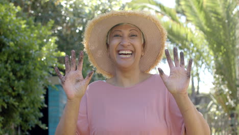 Portrait-of-happy-senior-biracial-woman-working-in-garden-and-spending-time-at-home