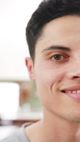 Vertical-video-half-portrait-of-happy-biracial-man-smiling-in-living-room,-copy-space,-slow-motion