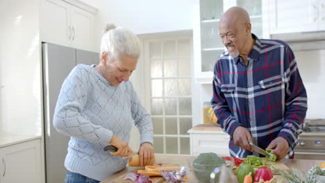 Feliz-Pareja-Diversa-Hablando-Y-Cortando-Verduras-En-La-Cocina,-Cámara-Lenta