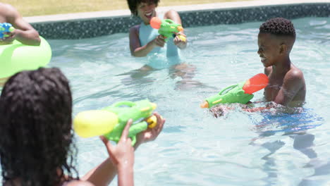 Felices-Padres-Afroamericanos,-Hijo-E-Hija-Jugando-Con-Pistolas-De-Agua-En-La-Piscina,-Cámara-Lenta