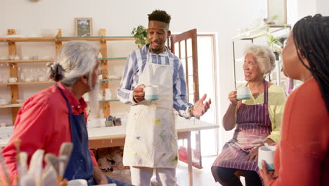 Happy-diverse-group-of-potters-having-break-and-discussing-in-pottery-studio