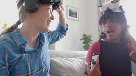 Happy-diverse-teenage-female-friends-playing-video-games-with-vr-headsets-at-home,-slow-motion