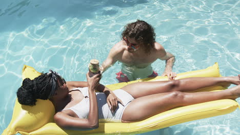 Una-Pareja-Diversa,-Una-Joven-Afroamericana-Y-Un-Hombre-Caucásico,-Disfrutan-De-Un-Día-Soleado-En-La-Piscina