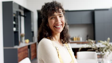 Portrait-of-happy-mature-caucasian-woman-with-long-curly-hair-smiling-at-home,-slow-motion