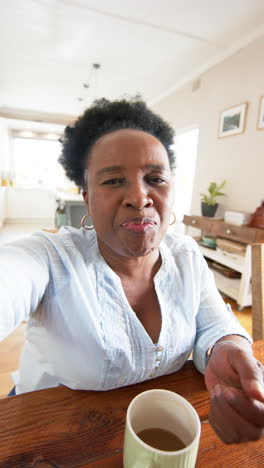 Mujer-Mayor-Afroamericana-Con-Taza-De-Café-Haciendo-Videollamada-En-Una-Habitación-Soleada,-Cámara-Lenta