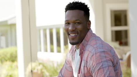 Portrait-of-happy-african-american-man-with-with-short-hair-in-garden-at-home,-slow-motion