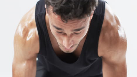 Determined-young-biracial-man-athlete-focused-on-his-workout,-ready-to-run-a-race-on-a-white-backgro