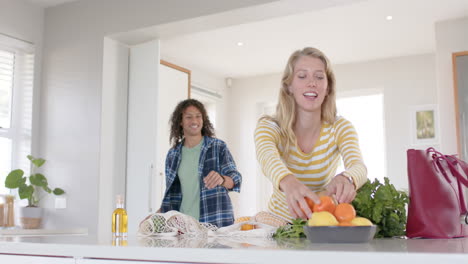 Happy-diverse-couple-unpacking-shopping-bags-in-ktichen,-slow-motion