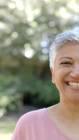 Vertical-video-of-portrait-of-happy-senior-biracial-woman-in-garden,-slow-motion