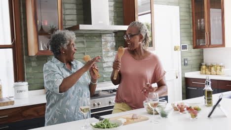 Felices-Amigas-Afroamericanas-Mayores-Preparando-Comida-Y-Cantando-En-La-Cocina,-Cámara-Lenta