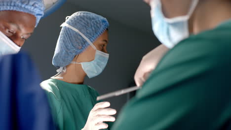 Diverse-female-and-male-surgeons-in-masks-passing-surgical-tools-during-operation,-slow-motion