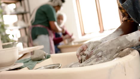 Hands-of-african-american-male-potter-using-potter's-wheel-in-pottery-studio,-slow-motion