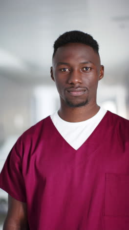 Vertical-video-of-portrait-of-happy-african-american-male-doctor-in-hospital,-slow-motion