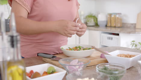 Sección-Media-De-Una-Mujer-Birracial-De-Talla-Grande-Haciendo-Comida-Con-Verduras-En-La-Cocina,-Cámara-Lenta