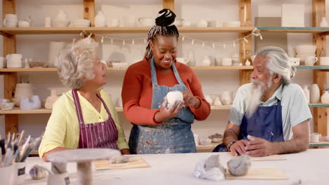 Happy-diverse-group-of-potters-discussing-about-work-in-pottery-studio