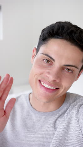 Vertical-video-of-happy-biracial-man-having-video-call-smiling-and-waving,-slow-motion